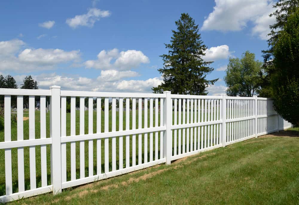 White vinyl fence by green lawn - Big Easy Fences