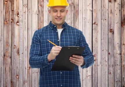 smiling male builder in helmet with clipboard - Big Easy Fences