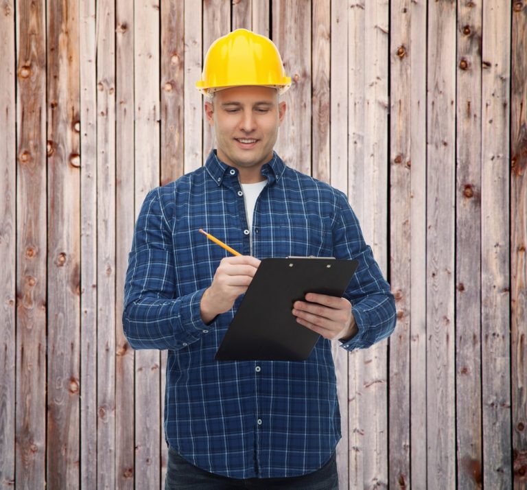smiling male builder in helmet with clipboard - Big Easy Fences