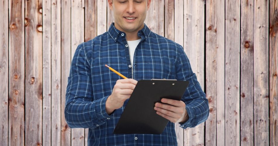 smiling male builder in helmet with clipboard - Big Easy Fences