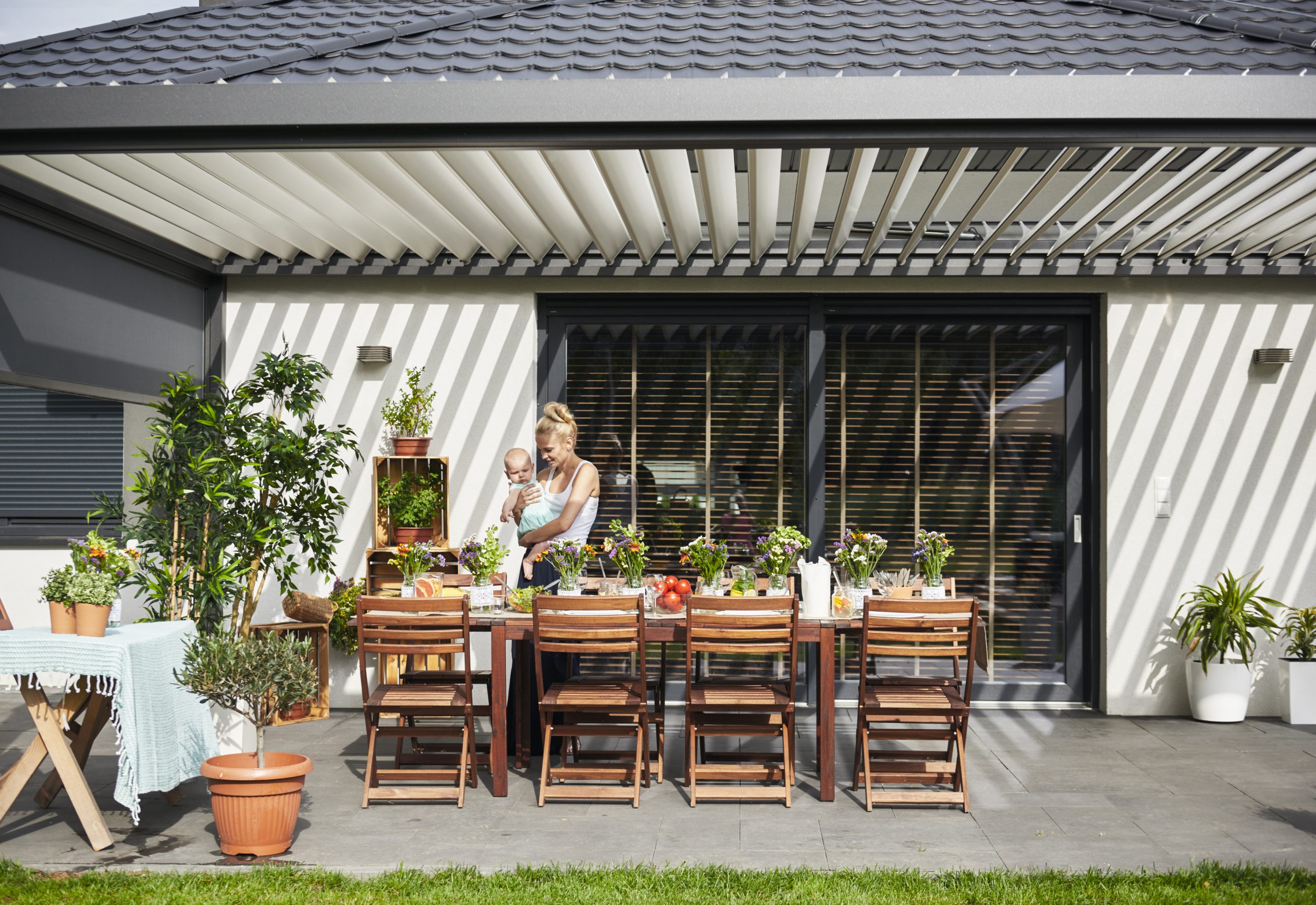 Woman carrying baby at under a pergola with tables and chairs - Big Easy Fences